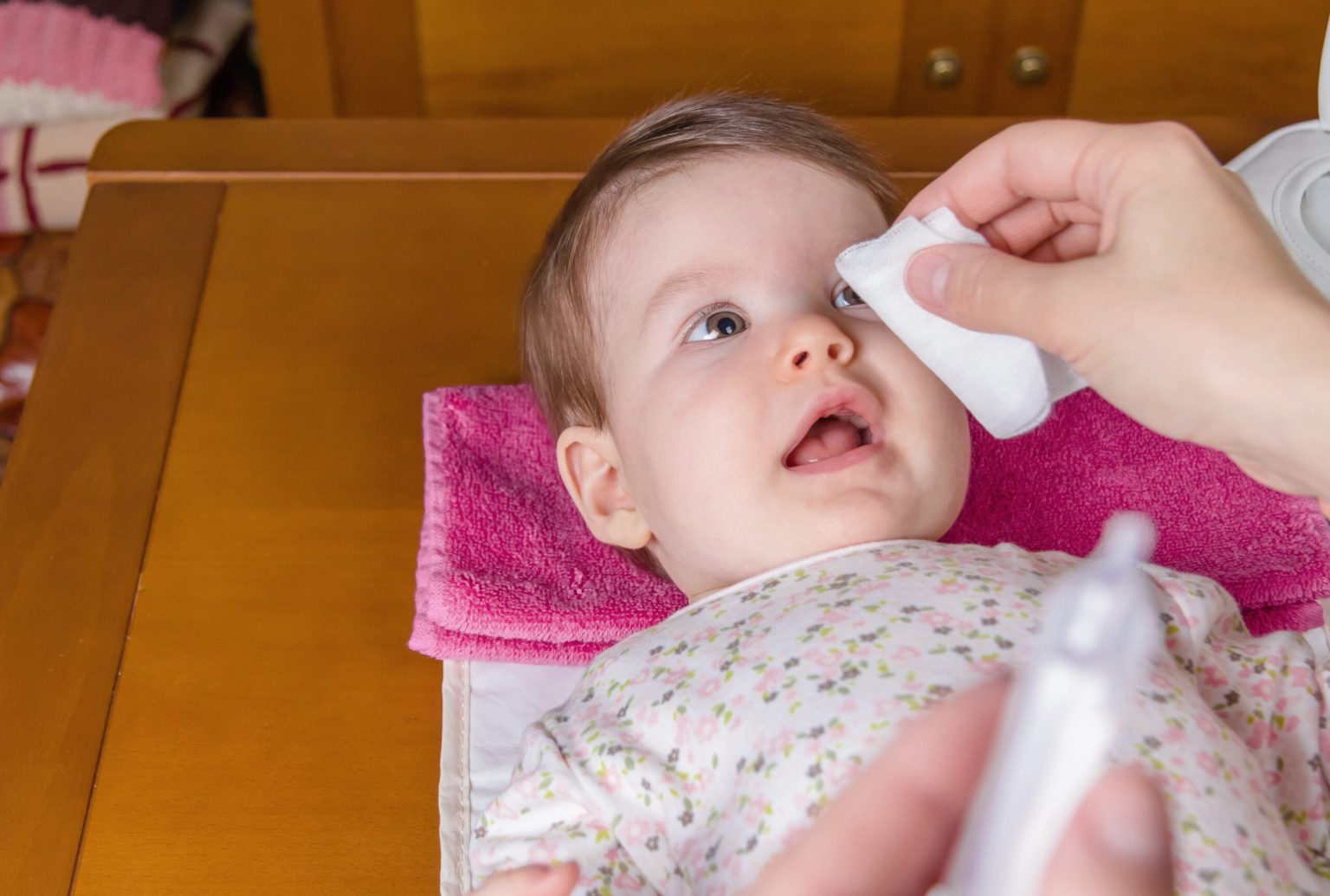 closeup of mother hands cleaning eyes of baby with physiological serum in cotton scaled 1