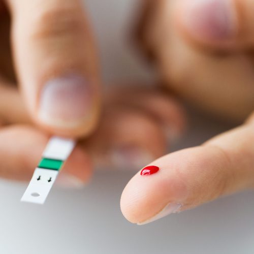 medicine, diabetes, glycemia, health care and people concept - close up of male finger with blood drop and test stripe