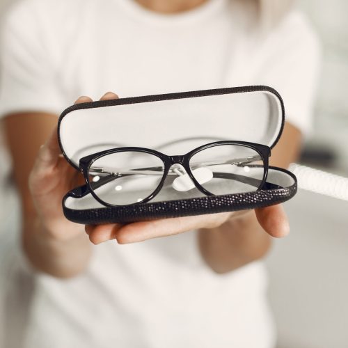 Woman choosing glasses at optics store Girl in the store. Woman in a white t-shirt.